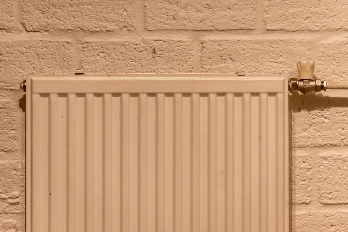 White radiator on a textured brick wall