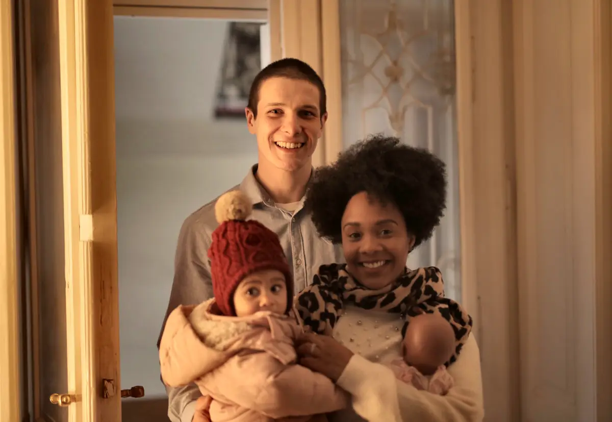 Smiling parents holding their baby in a warm doorway at home