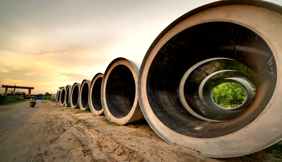 Large sewer pipe sections lined up on a site at sunset