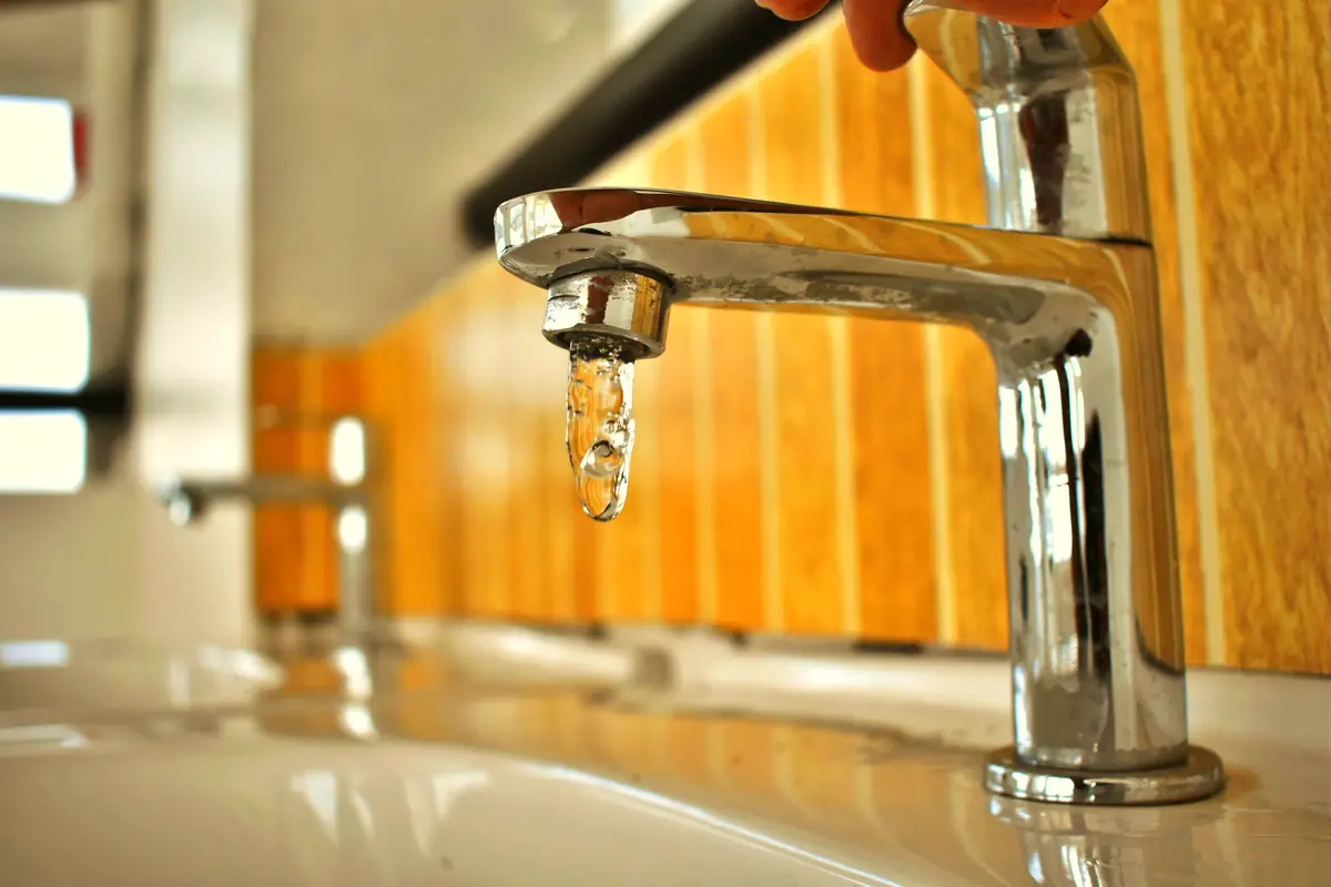 Water drop forming on a chrome faucet