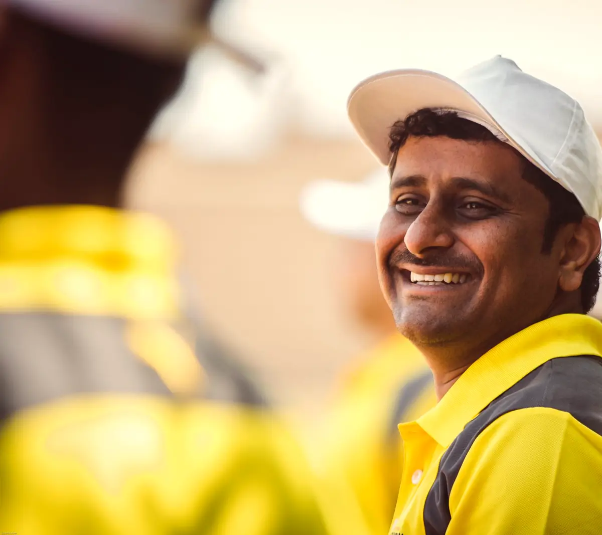 Cheerful crew member in a cap and work jacket, laughing with the team