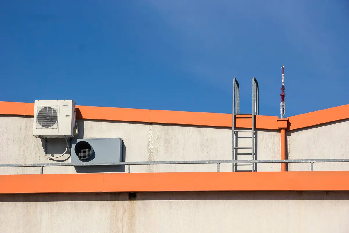 Air conditioner on a flat roof beside a ladder